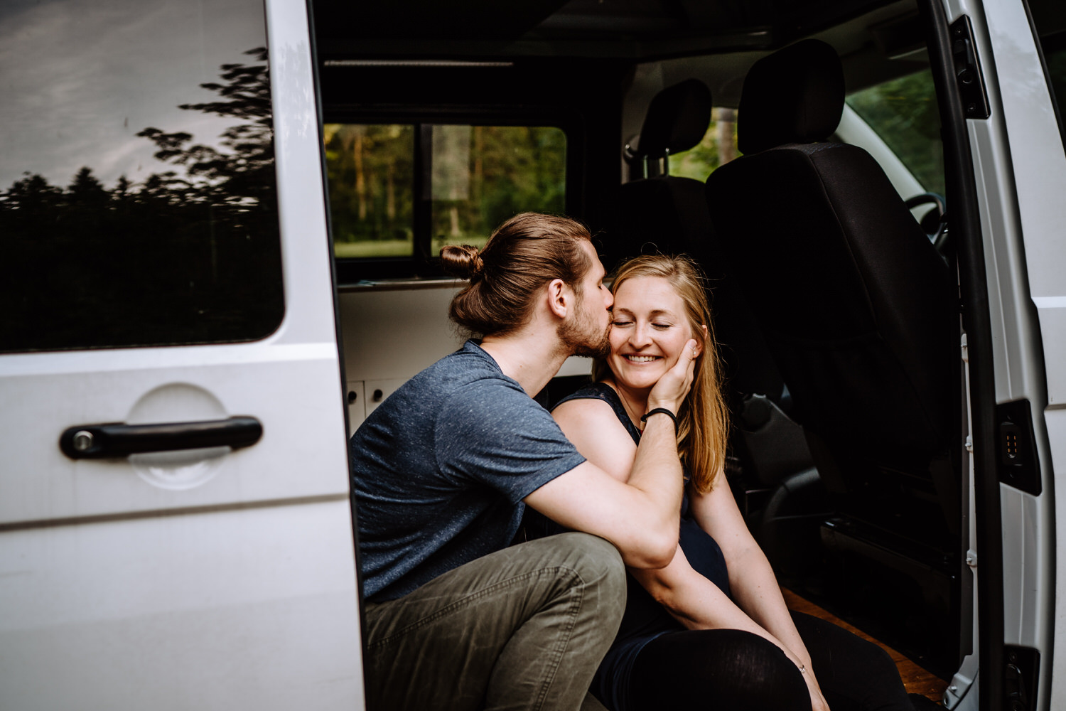 Verliebtes Pärchen in der Tür von ihrem VW Camper inmitten der wunderschönen Natur am Schwansee im Allgäu
