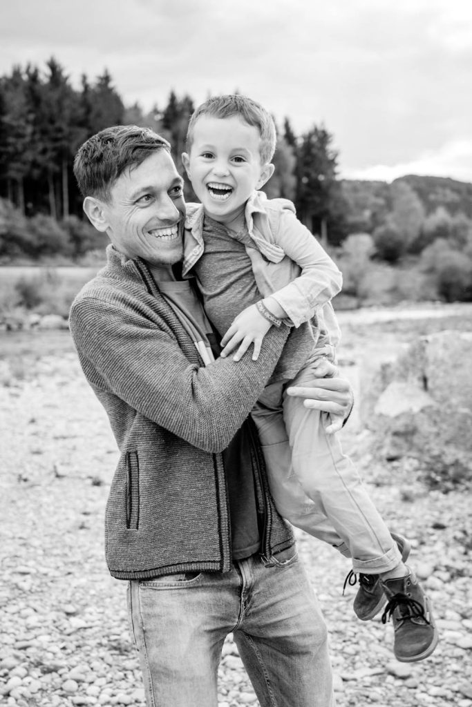 Papa hält Sohn im Arm bei Familienfotos an der Ammer