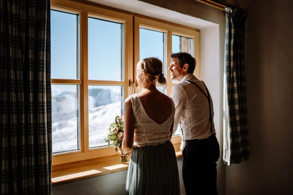 Brautpaar schaut aus dem Fenster kurz vor der standesamtlichen Hochzeit auf der Zugspitze
